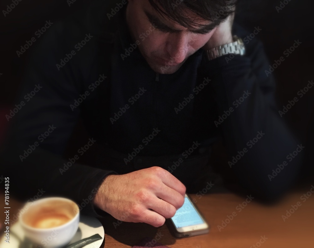 man sitting with coffee looking worried at his phone man sitting with coffee looking worried at his phone
