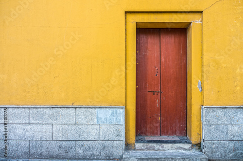 Vintage building with red wooden door and yellow concrete wall © joeyphoto