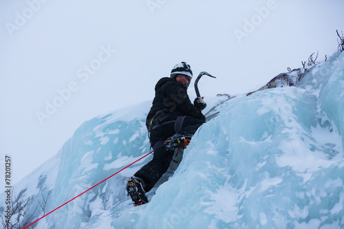 Ice climber ascending a frozen waterfall photo