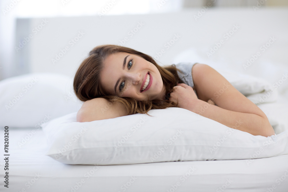 Young beautiful smiling woman lying on the bed at home Young beautiful smiling woman lying on the bed at home