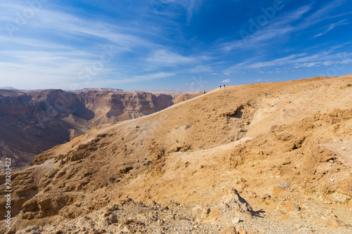 Group of people ascending desert mountain slope.