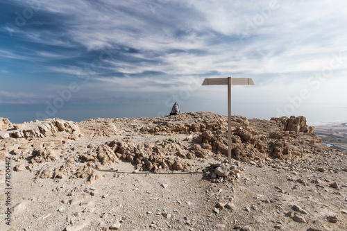 Woman sitting desert mountain edge above sea. photo