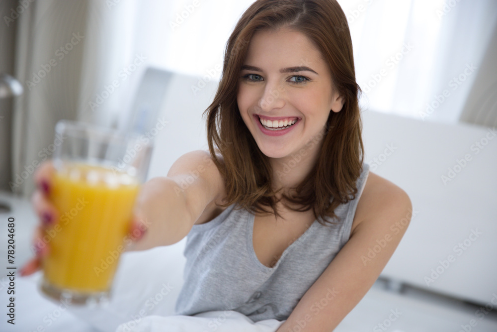 Smiling woman holding orange juice on the bed Smiling woman holding orange juice on the bed