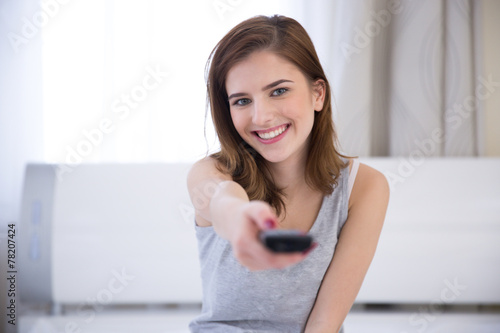Free Download Happy woman sitting on the bed with remote control - GFXLoad