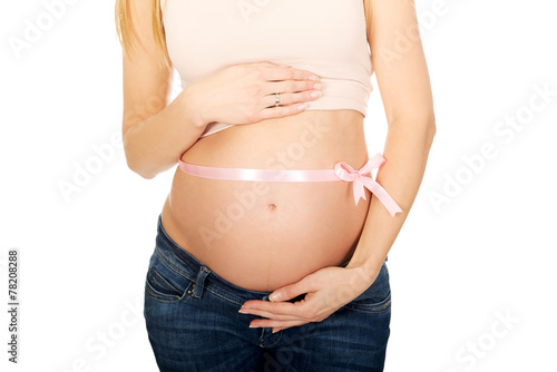 Pregnant woman belly with pink ribbon gift © Piotr Marcinski