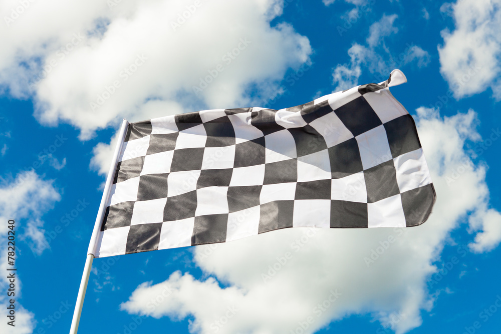 Checkered flag waving with blue sky and clouds behind it