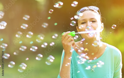 Gorgeous young brunette girl blowing soap bubbles