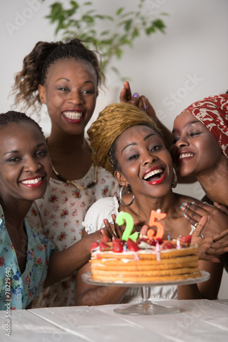 Girl looking at birthday cake surrounded by friends