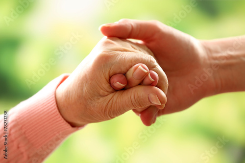 Old and young holding hands on light background, closeup © Africa Studio