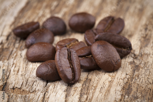 roasted coffee beans in wooden spoon placed on coffee beans as b