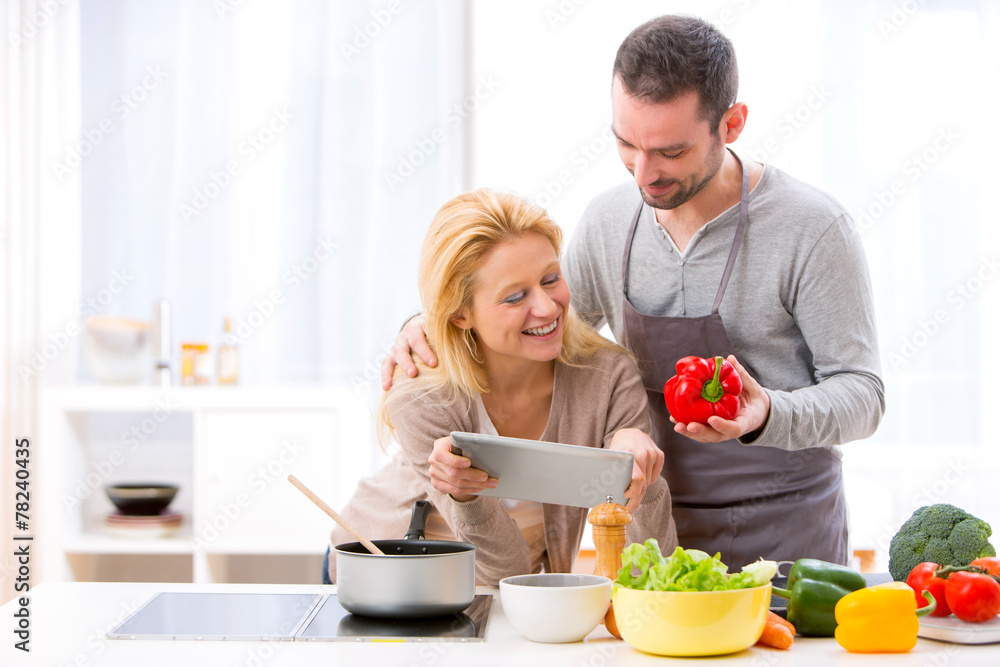 Young attractive couple reading recipe on a  tablet