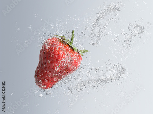 Ripe red strawberry splashing into water