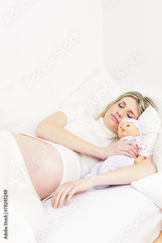 pregnant woman sleeping in bed with a doll