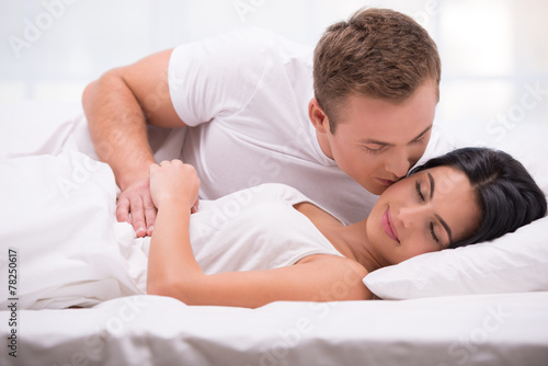 Young man kissing his sleeping wife