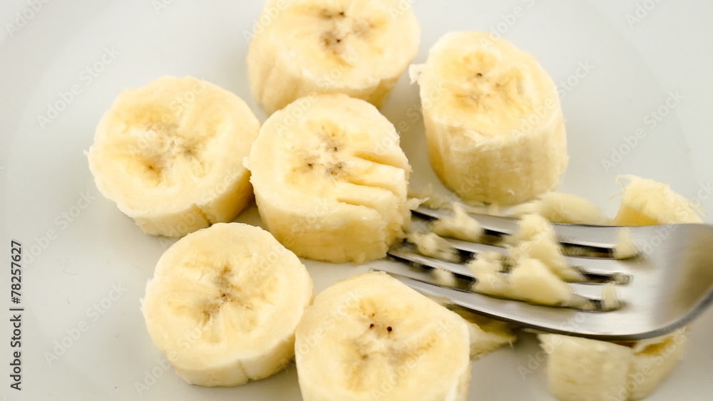 Mashing banana pieces into paste with fork Mashing banana pieces into paste with fork