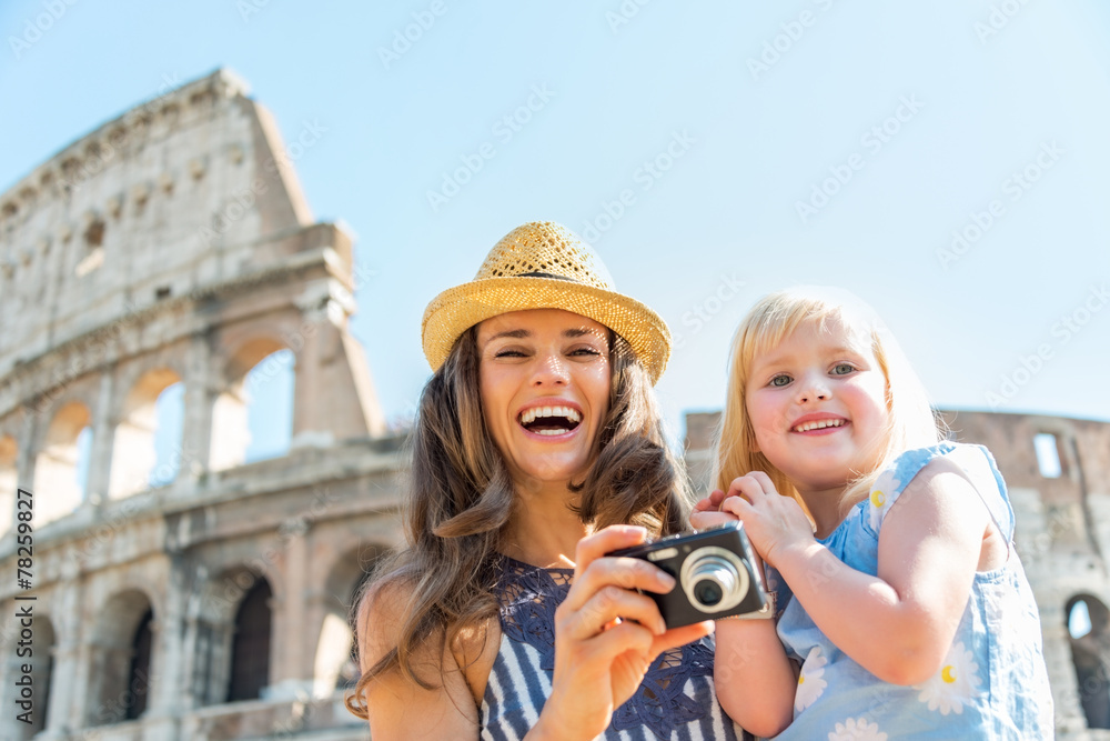 Happy mother and baby girl with photo camera near colosseum