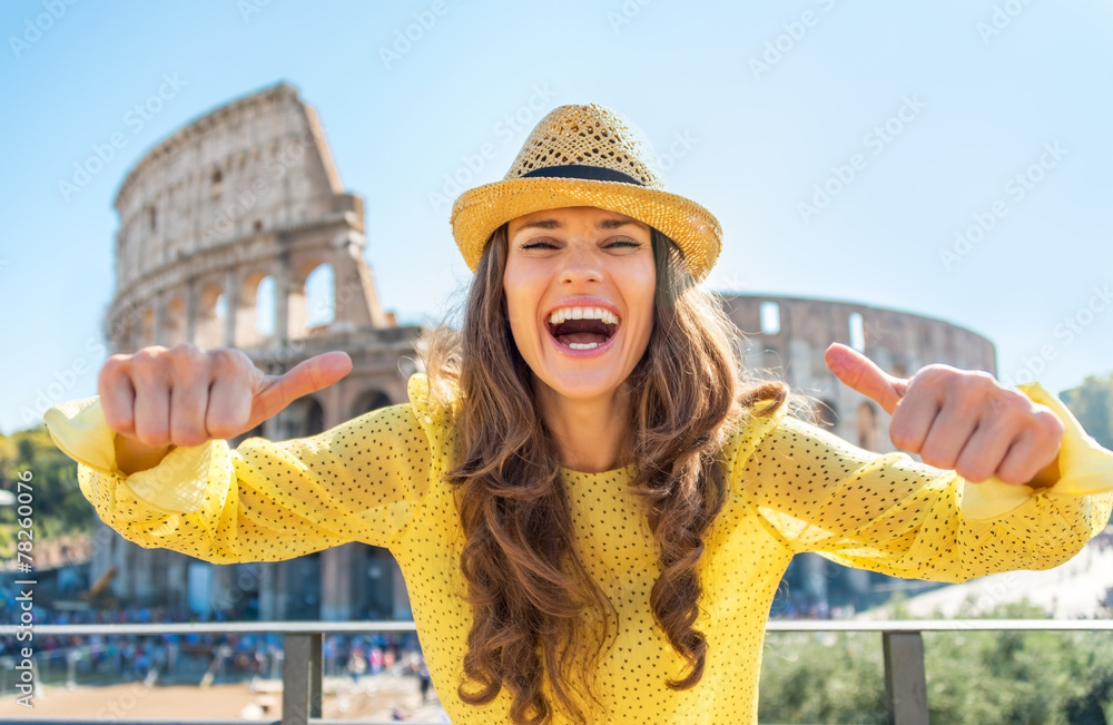 Young woman showing thumbs up in front of colosseum in rome
