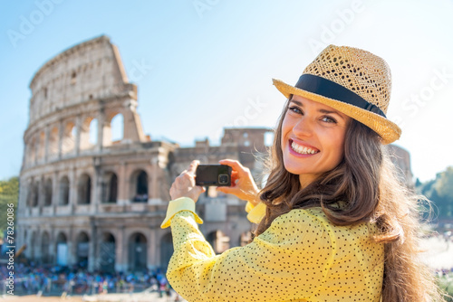 Fotografie Happy young woman taking photo of colosseum in rome, italy