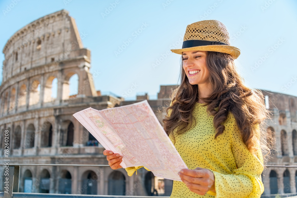 Happy young woman with map in front of colosseum in rome, italy