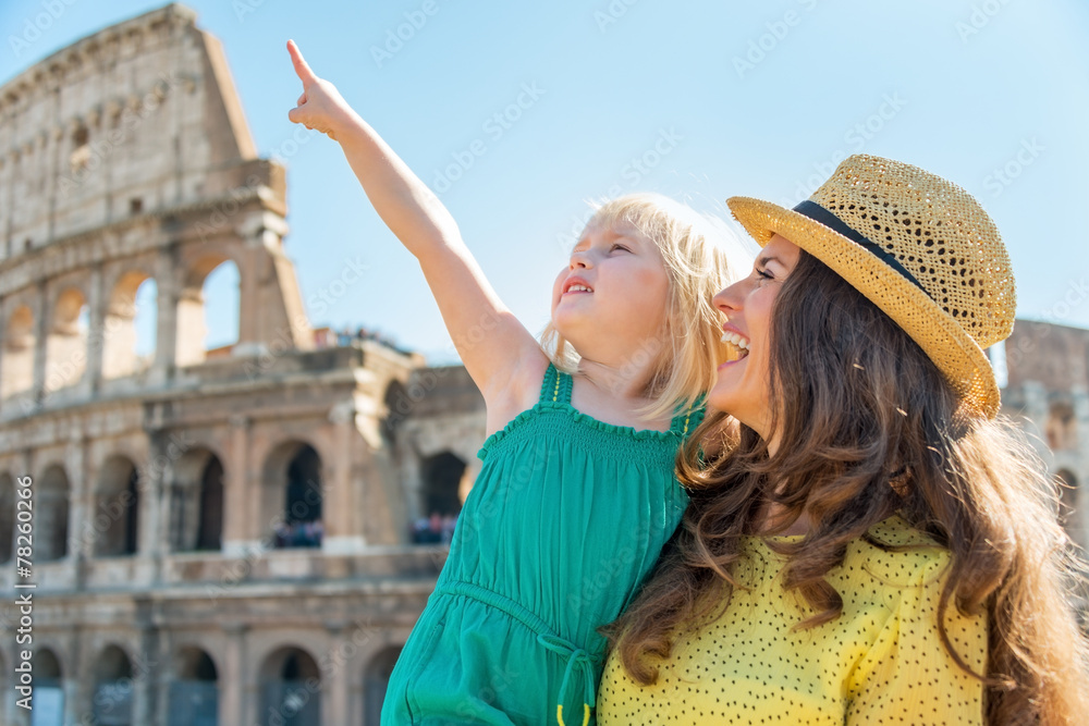 Happy mother and baby girl pointing in front of colosseum
