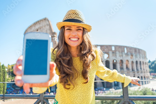 Sticker Happy young woman showing cell phone in front of colosseum