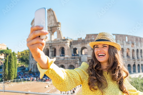 Canvas Print Smiling young woman taking photo with cell phone in Rome