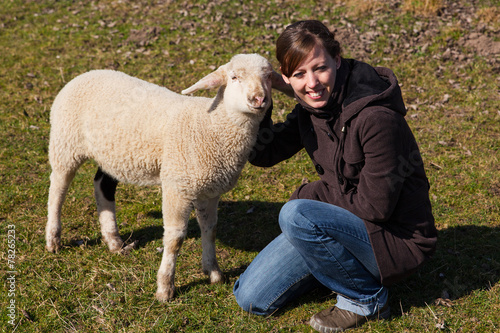 Frau kniet neben kleinem Lamm photo