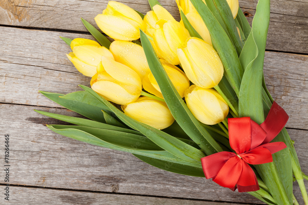Fresh yellow tulips bouquet over wooden table background Fresh yellow tulips bouquet over wooden table background