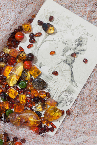 Amber colored stones and old post card on fabric background