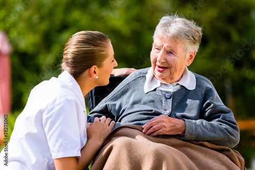 Pflegerin hält Hand alter Frau im Rollstuhl photo