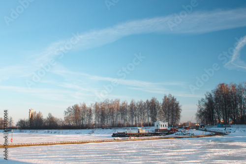 Striped landscape - ice on the river, boat station and blue sky