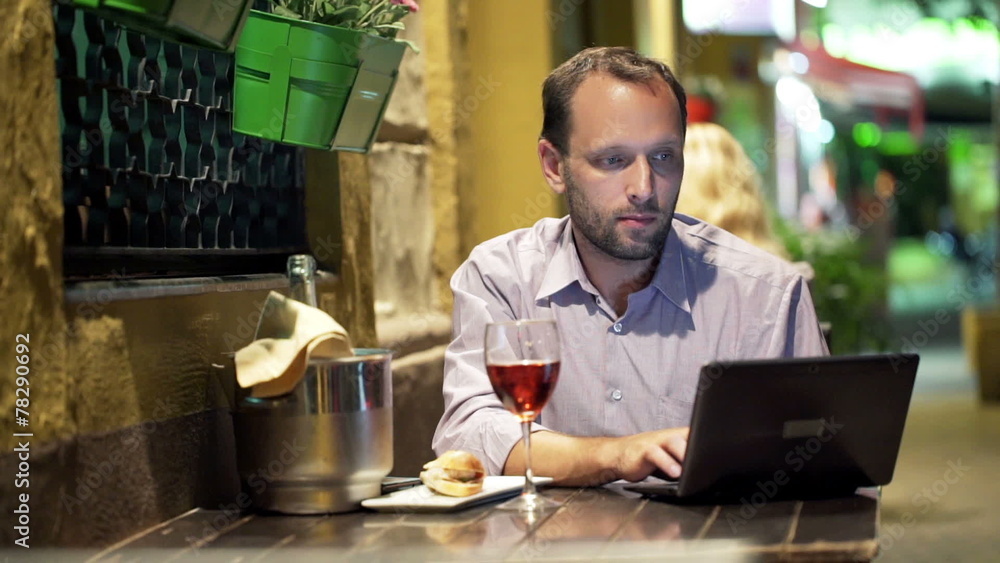 Young man using laptop while sitting in cafe at night Young man using laptop while sitting in cafe at night