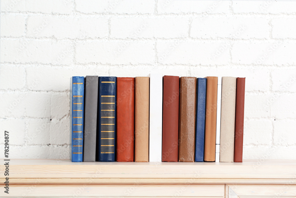 Naklejka premium Books on shelf on wall background