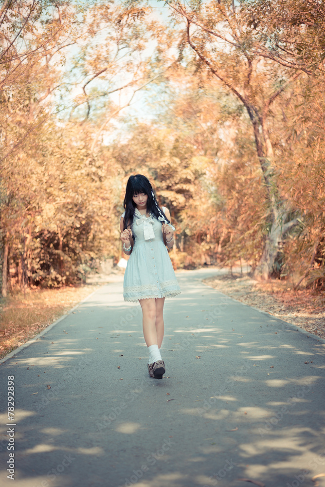 A cute Asian Thai girl is walking on a forest path alone in soft A cute Asian Thai girl is walking on a forest path alone in soft