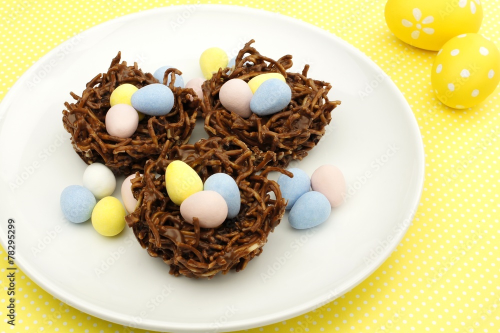 Fototapeta premium Springtime chocolate nests filled with Easter eggs on yellow