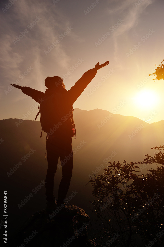 	cheering woman open arms at sunrise mountain peak