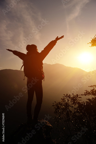  cheering woman open arms at sunrise mountain peak