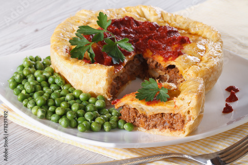 Meat pie and green peas on a plate. horizontal