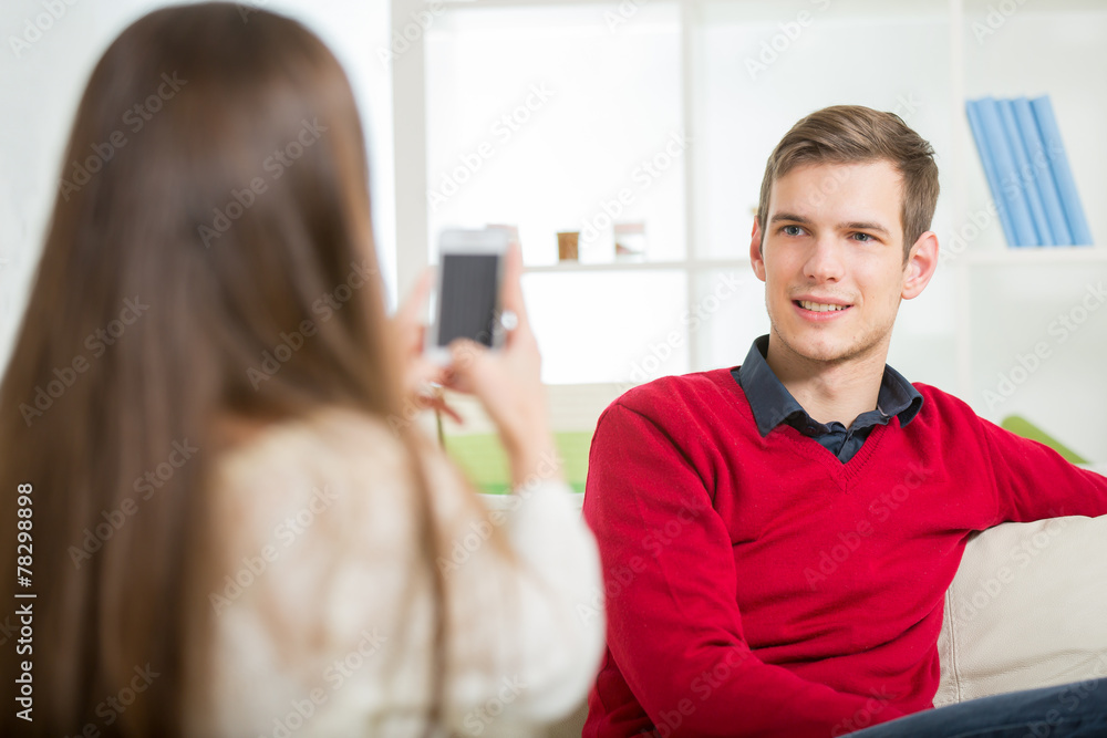 Girl photographs her boyfriend in the living room. Girl photographs her boyfriend in the living room.