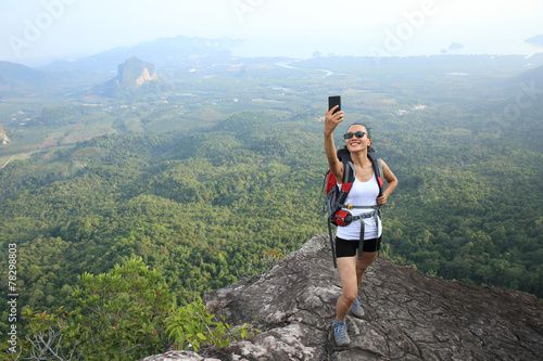 woman hiker taking photo with smart phone at mountain peak