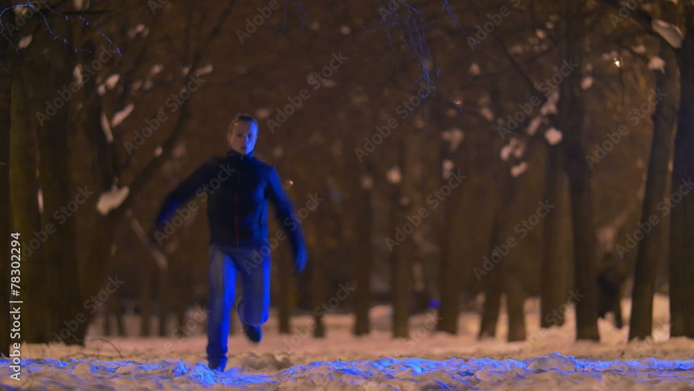 Man running at night park by trees and cars on the background Man running at night park by trees and cars on the background