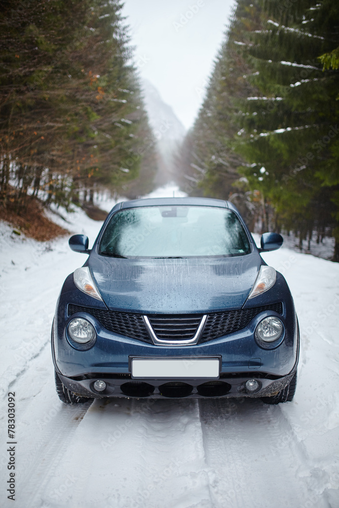 Naklejka premium Blue car on snowy road, wintertime