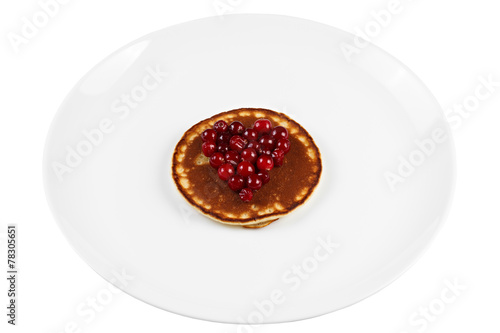 Fried pancakes with cranberry heart shaped with honey on a plate