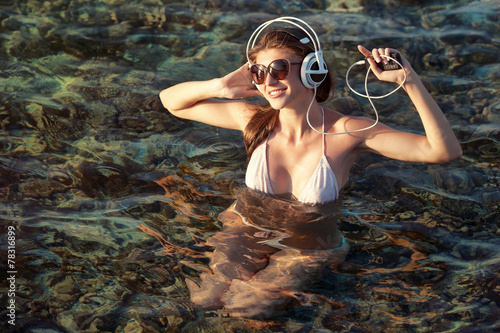 Young woman in headphones listening music and enjoying beautiful