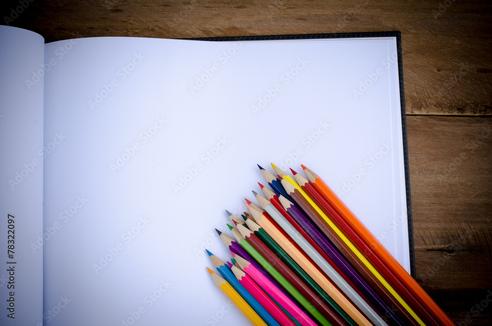 Fototapeta premium Color pencil and sketchbook on wooden background
