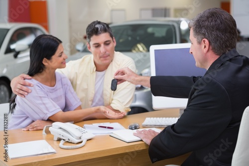 Salesman giving car keys to a couple