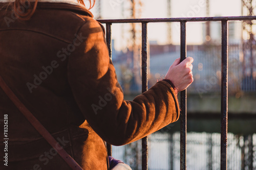Woman grabbing a fence by a canal