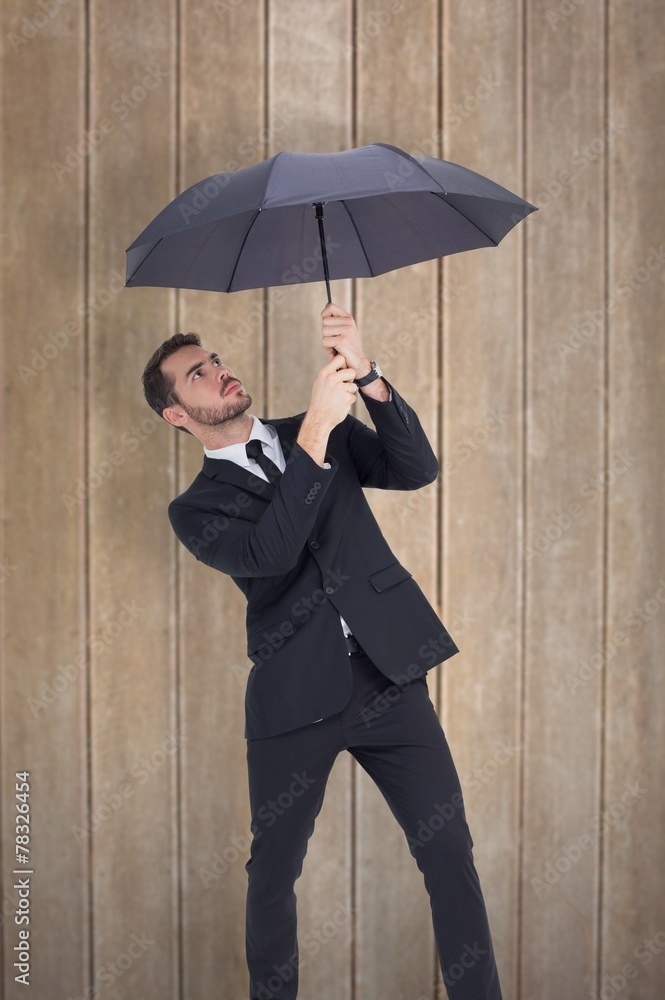 Composite image of businessman standing under black umbrella Composite image of businessman standing under black umbrella