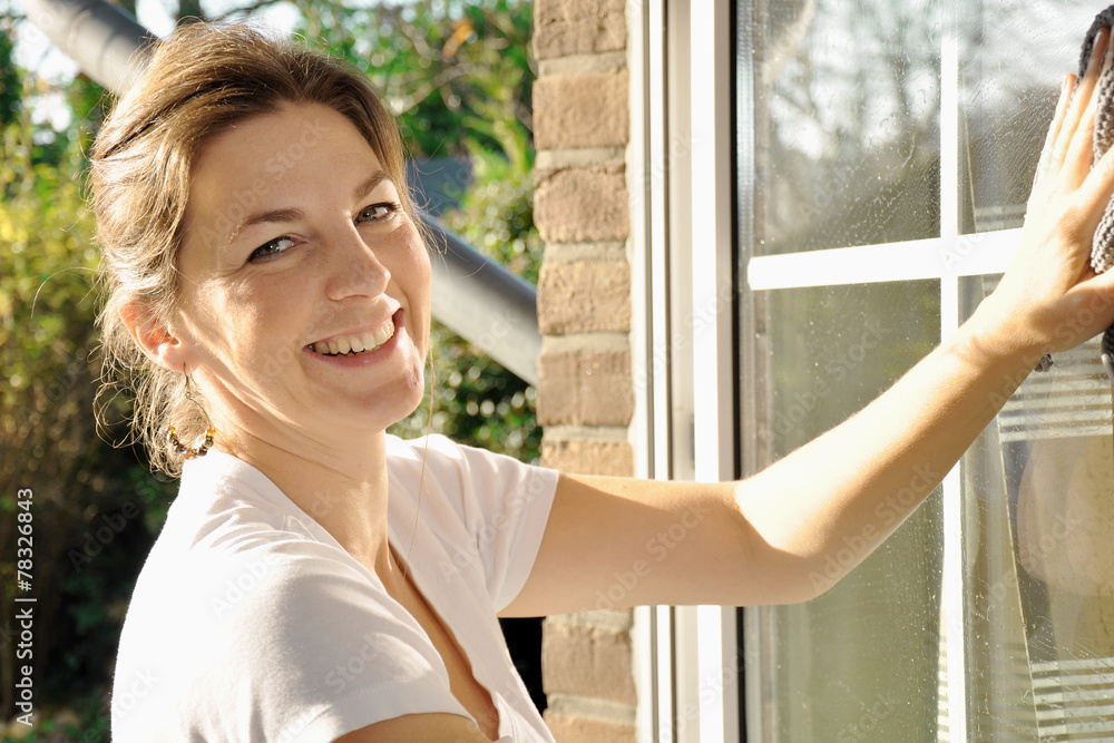 Frau hat Freude bei Fensterputzen und Hausarbeit