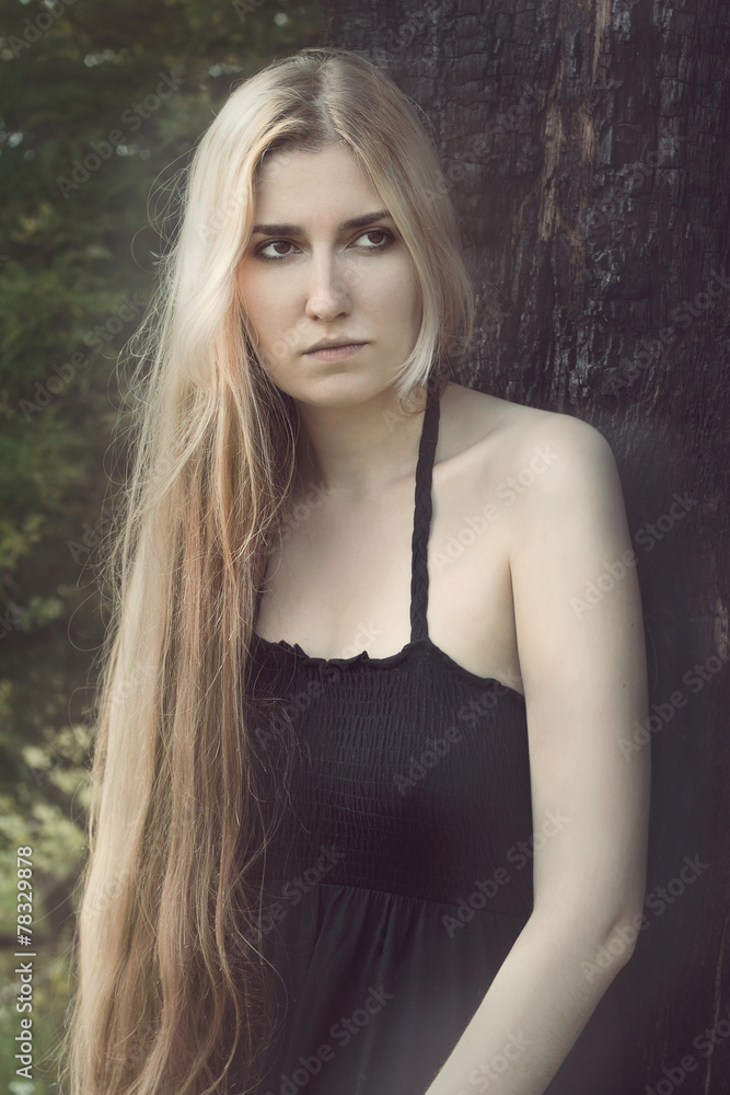 Fototapeta premium thoughtful woman standing under the burnt tree